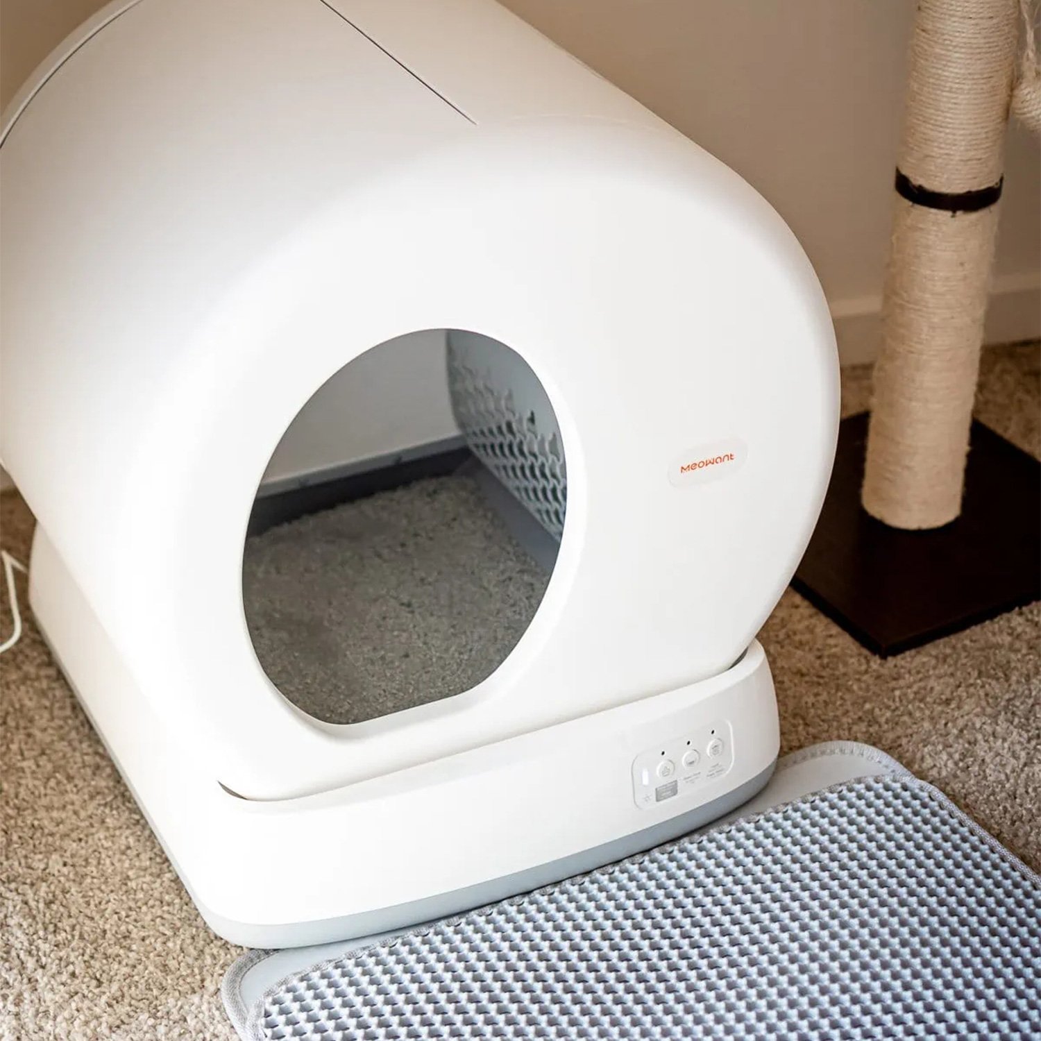 Close-up view of the automatic litter box in a home setting with a mat.